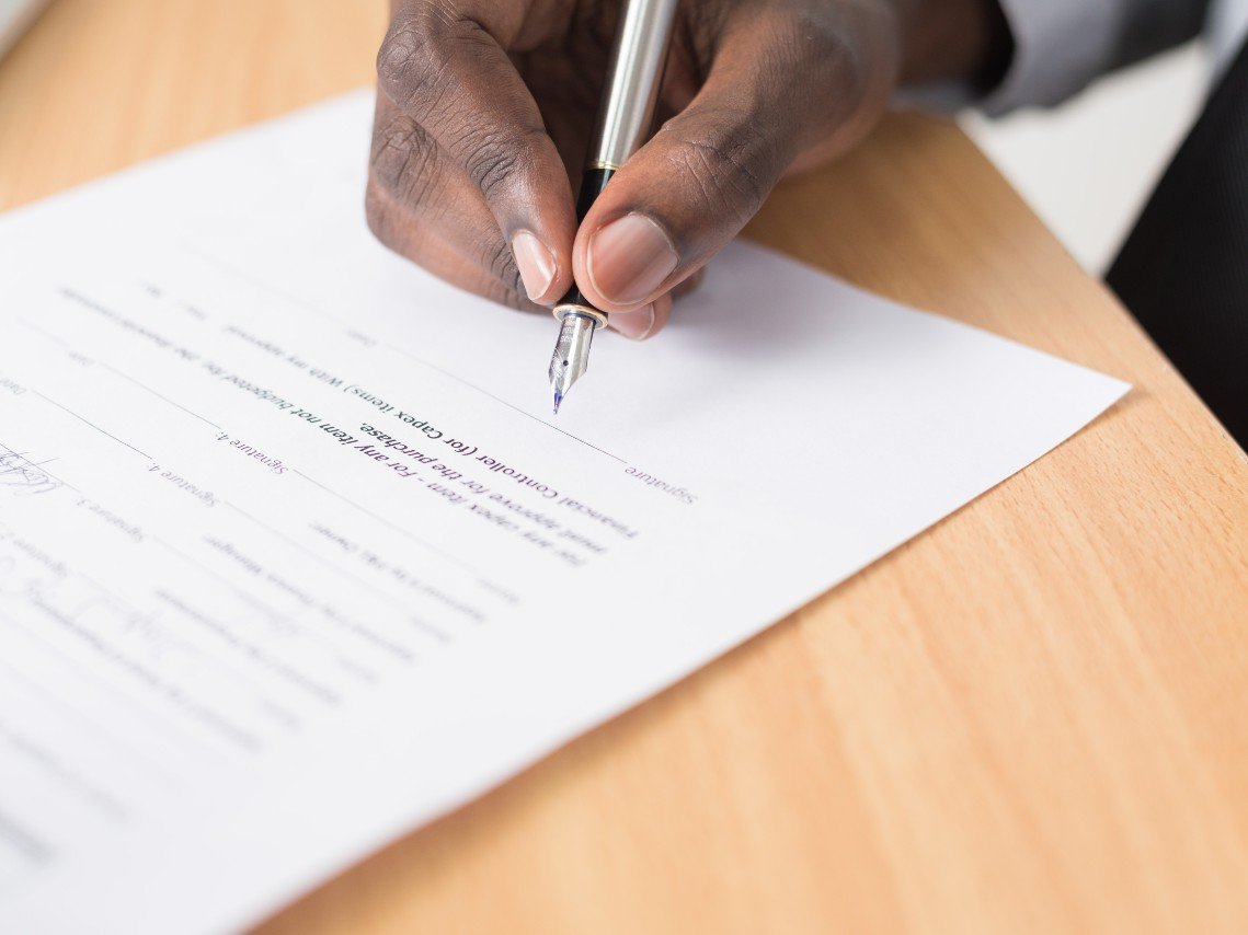 A close-up on a man's hand signing a document.