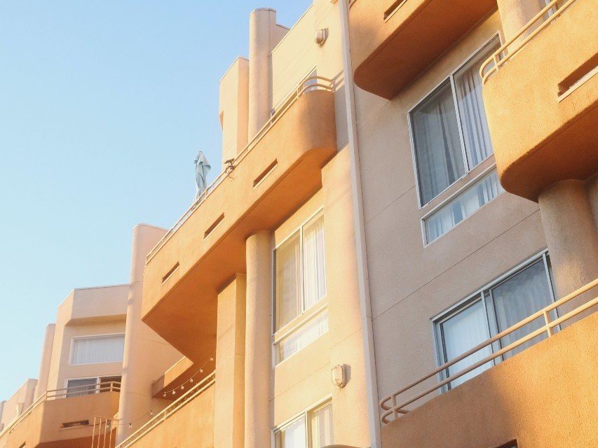 Ground-up angle of an apartment building with a tan exterior..